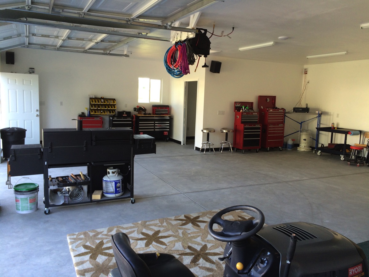 Wide view of the finished shop interior with tool chests and a riding mower